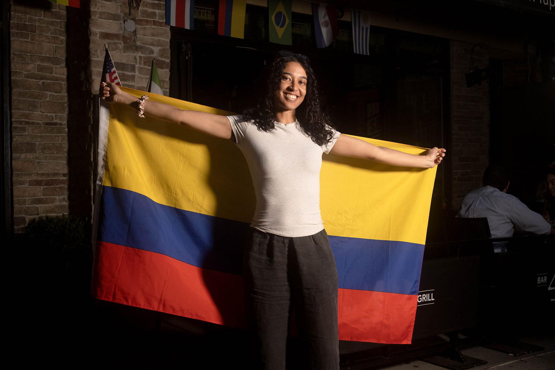 A portrait of a person while raising a Colombian flag at Bar 43 in Queens