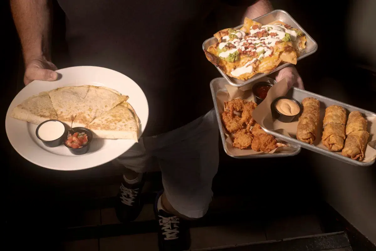 A waiter holds food plates at Bar 43 in Queens. 