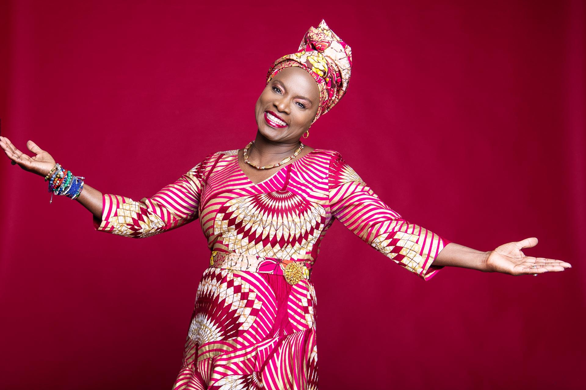 A portrait of Angélique Kidjo on a pink backdrop