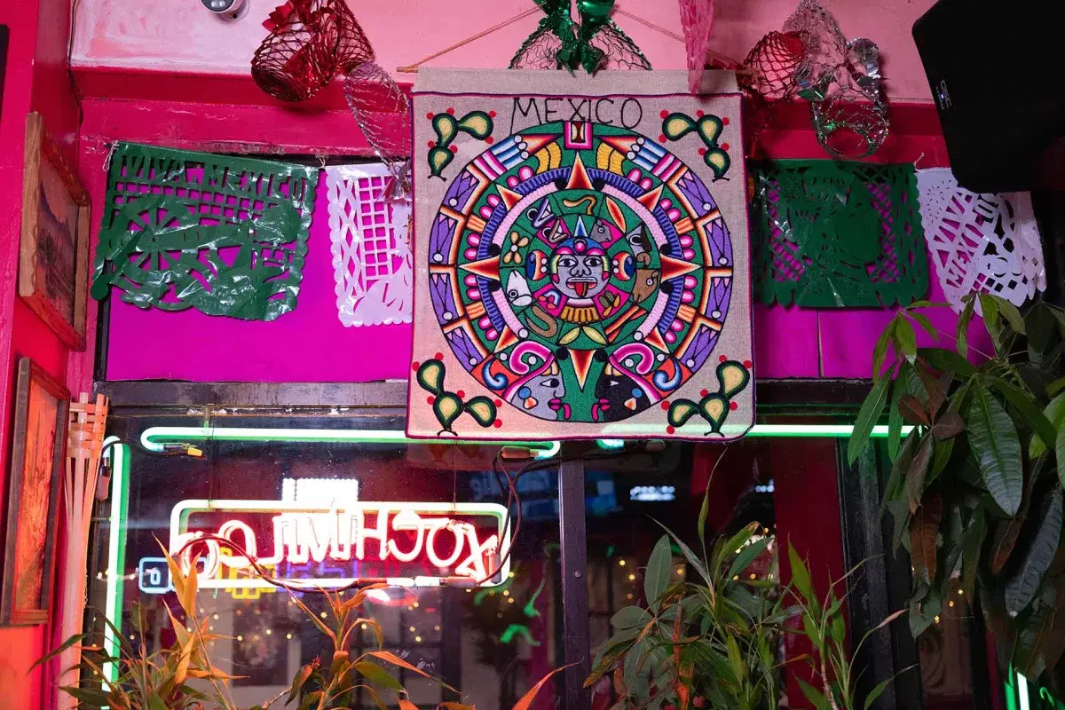 The Aztec calendar, and papel picado on a pink wall at Xochimilco