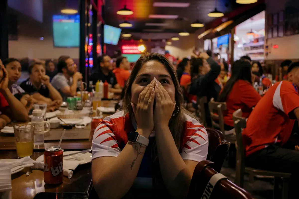 A person covers their face with their hands while watching the game.