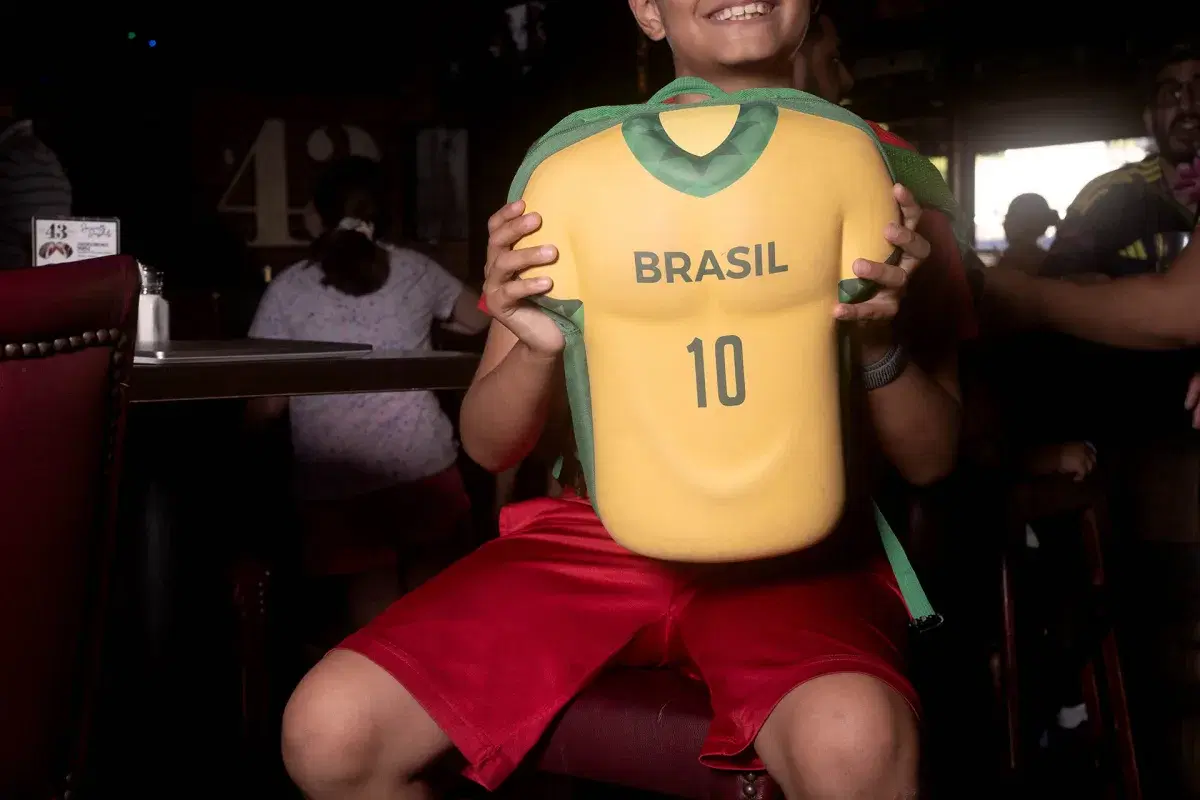 A young person holds a Brasil backpack with the number 10 on it.