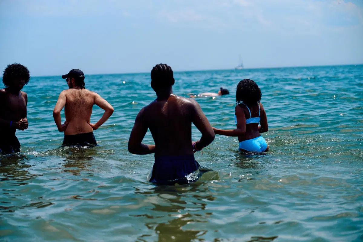 A group of people stand up inside the ocean at Brighton Beach in Brooklyn. 