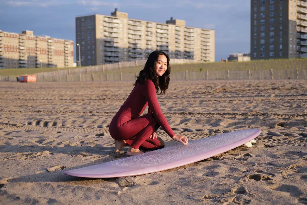 Portrait of a person with their surfboard at Rockaway Beach in Queens. 