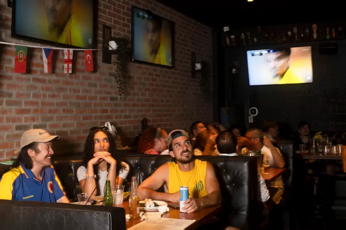 Three people watch the Colombia vs Costa Rica game at Bar 43 in Queens. 