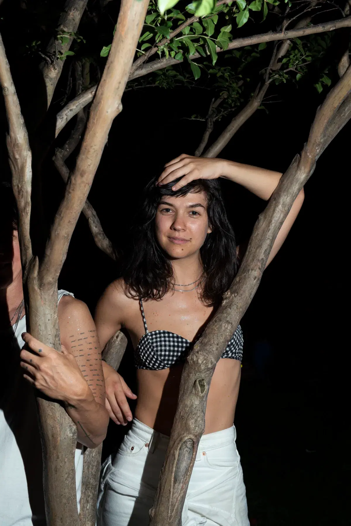 Person posing behind tree