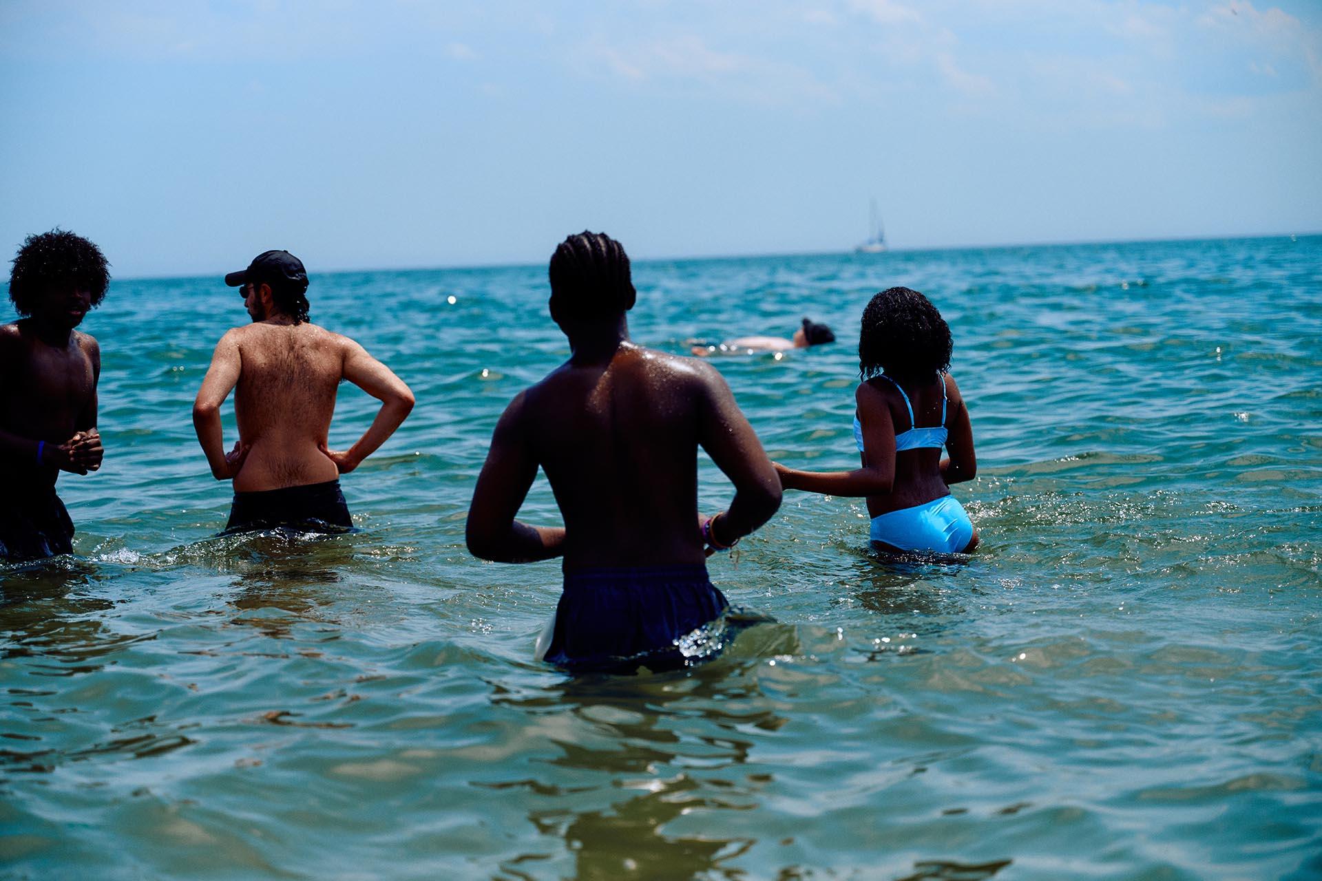 A group of people stand up inside the ocean at Brighton Beach in Brooklyn.